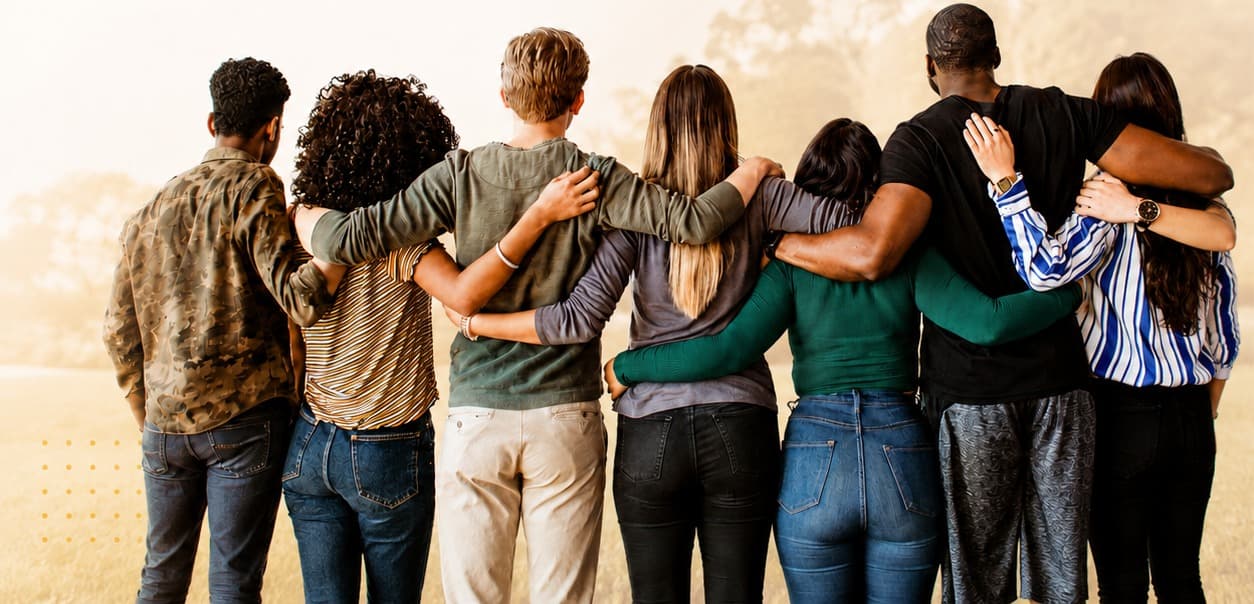 Un grupo de personas abrazadas de espaldas, mirando juntas el horizonte